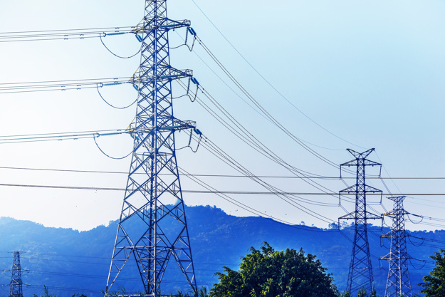 electricity transmission pylon silhouetted against blue sky at dusk